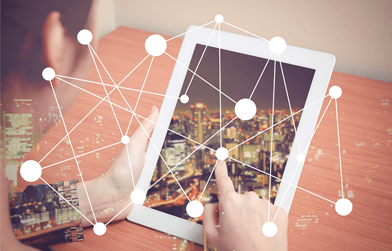 A tablet showing a city at night overlaid with a mesh of network connections